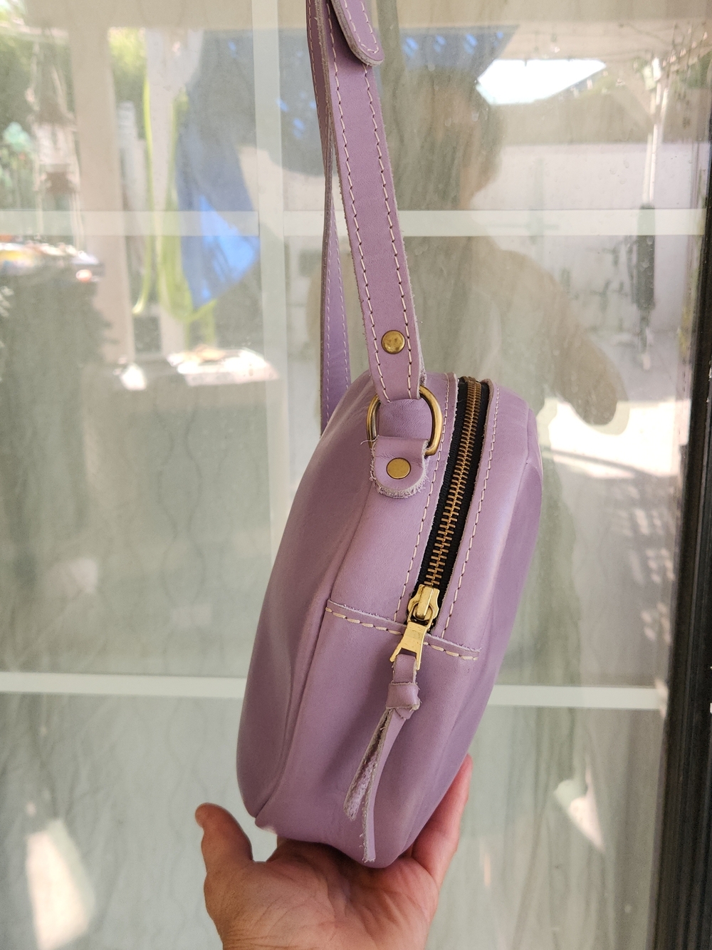 The purple round bag in the image is a Circle Crossbody in the color Lavender - Picture 7 of 8